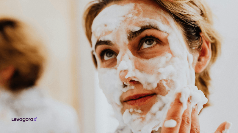 Excesso de limpeza da pele e efeito rebote na oleosidade Mulher com o rosto coberto de espuma durante limpeza facial, representando excesso de lavagem da pele e seus efeitos um dos erros de skincare