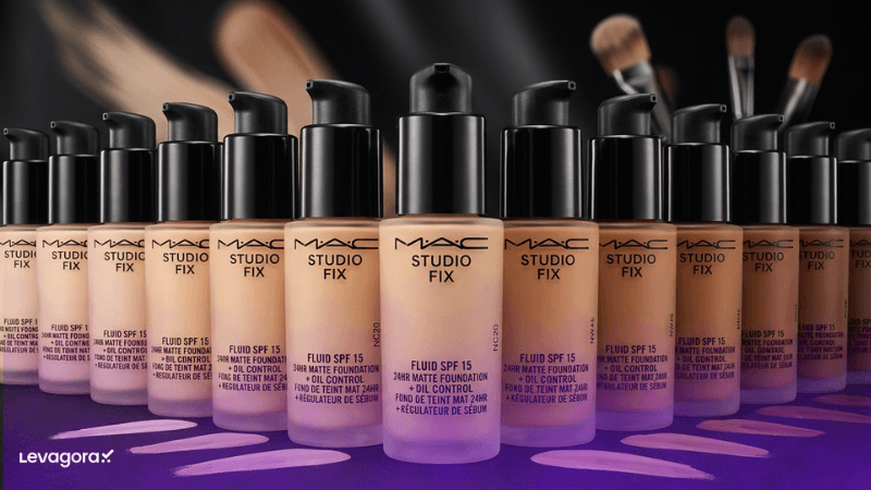Base Studio Fix Fluid da marca de maquiagem M.A.C. Cosmetics Frascos da base Studio Fix Fluid da marca de maquiagem M.A.C. Cosmetics alinhados em diversos tons de pele, com pincéis ao fundo.